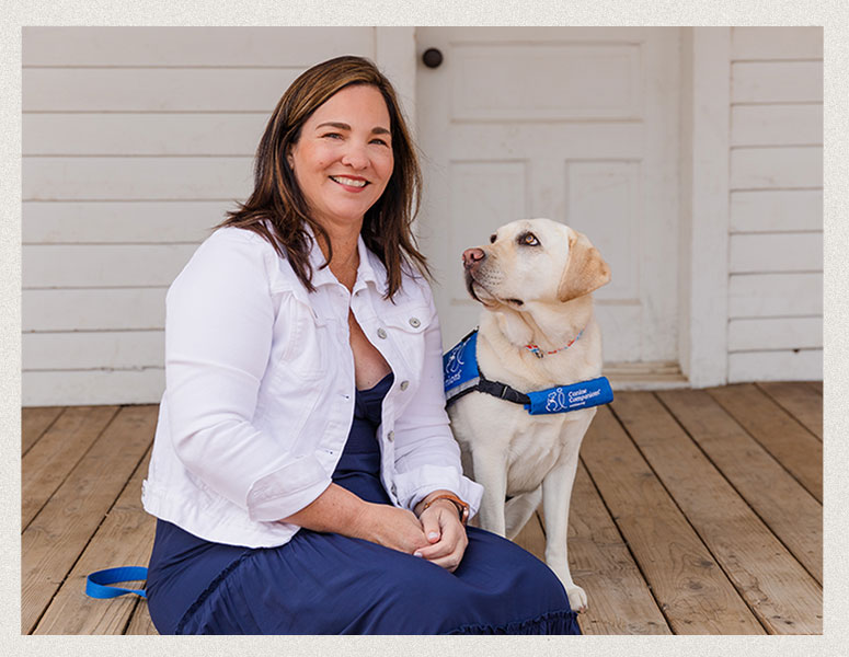 Amy Black-Ryel sitting on a wooden porch with her therapy dog beside her, captured in a natural, relaxed moment.