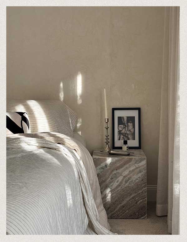 Natural light pouring in the window of a boutique hotel room with a marbled side table.