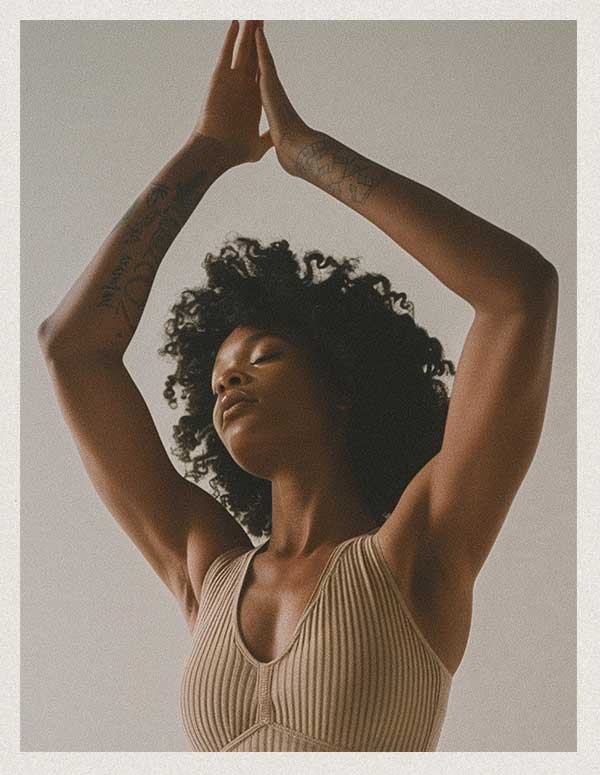Woman practicing yoga with prayer hands and a beige yoga top.