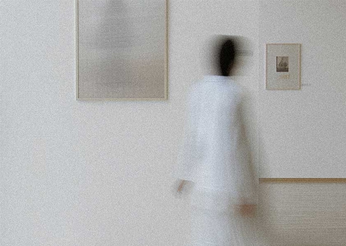 collector-in-art-gallery A collector is browsing an art gallery to buy artwork that is hanging on the cream walls.