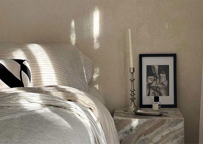 luxury-hotel-room-velvet-fern Luxury hotel room with marble bed stand, luxury linen bedspread, and light pouring through the window.