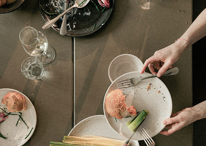 restaurant-table-velvet-fern Guests at a restaurant serving up dishes with bread and leeks. Wine glasses sit to the side